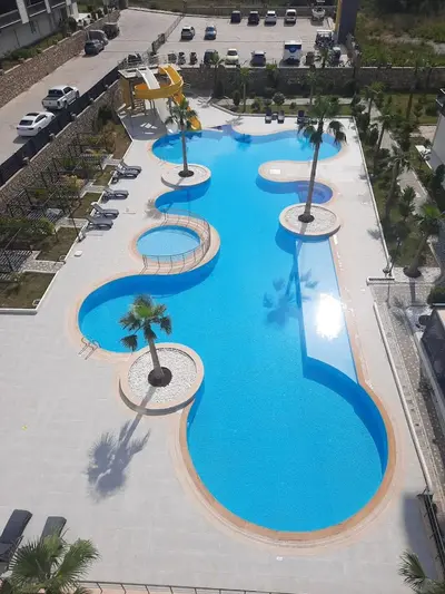 Bazen u hotelskom stilu na otvorenom sa zabavnim toboganima. Moderan, prostran vanjski bazen sa živopisnom plavom vodom, žutim toboganima i nekoliko palmi. Uključuje ležaljke i odvojeni manji, ograđeni bazen, savršen za porodice.