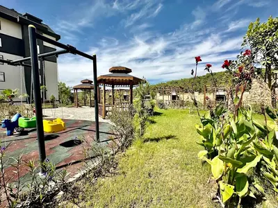 Igralište u stambenom kompleksu i bujni zeleni vrt. Živopisno vanjsko igralište sa šarenim ljuljačkama na mekom tlu, smješteno u bujnom, dobro održavanom vrtu sa više drvenih sjenica za društvena okupljanja i opuštanje, pored stambene zgrade.
