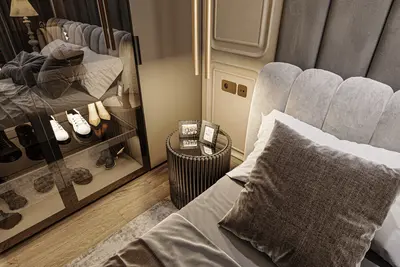 Luxury Modern Bedroom with Stylish Bed and Storage. A modern and luxurious bedroom featuring an upholstered headboard, warm lighting, and wood flooring. A stylish nightstand and a glass shoe cabinet are visible.