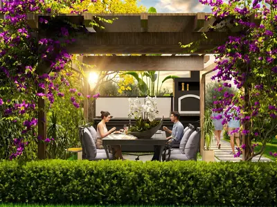 Luxurious Outdoor Dining Under Pergola with BBQ. A vibrant outdoor dining area under a wooden pergola draped with purple bougainvillea. Features a modern dining set and an outdoor BBQ kitchen, surrounded by lush green hedges and flowers, perfect for al fresco meals.