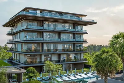 Luxury Apartment Building with Pool, Balconies and Lush Landscape. Modern luxury apartment building exterior with multiple balconies, a rooftop terrace, and a large outdoor pool area. Features include sun loungers, lush landscaping, and palm trees.