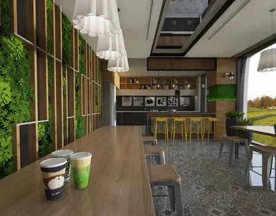 Modern Cafe Style Social Area with Green Wall. A modern, spacious social area featuring a striking vertical green wall and a long communal wooden table. Includes a bar with yellow stools and large windows offering an outdoor view. Stylish and inviting.