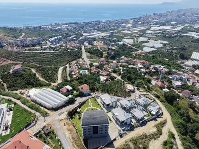 Panoramic Sea View Coastal Turkish Town with Modern Villas. An aerial view of a Turkish coastal town. It showcases modern villas on a hillside with panoramic views of the Mediterranean Sea, urban areas, and green landscapes.