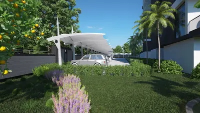 Modern Covered Parking with Lush Greenery and Palm Trees. An outdoor covered parking lot featuring modern white tensile structures over several parked cars. Lush green grass, vibrant lavender flowers, and an orange tree are in the foreground, with palm trees and a contemporary building in the background under a clear blue sky.