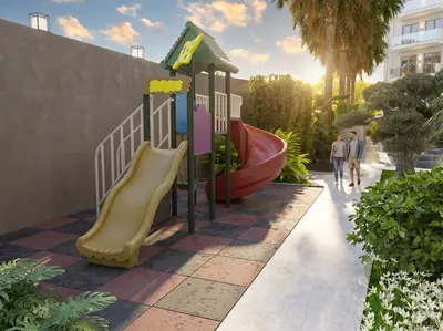 Vibrant Outdoor Children's Playground in Modern Residential Complex. A vibrant outdoor playground area in a modern residential complex, featuring yellow and red slides on safety flooring. Lush greenery and palm trees surround the space with a walking path nearby.