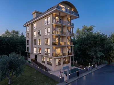 Modern Apartment Building Exterior with Balconies and Pool Area. Full exterior view of a modern apartment building at dusk. Features multiple balconies with glass railings, a distinctive curved roof, and a small illuminated outdoor swimming pool with lounge chairs surrounded by green trees.
