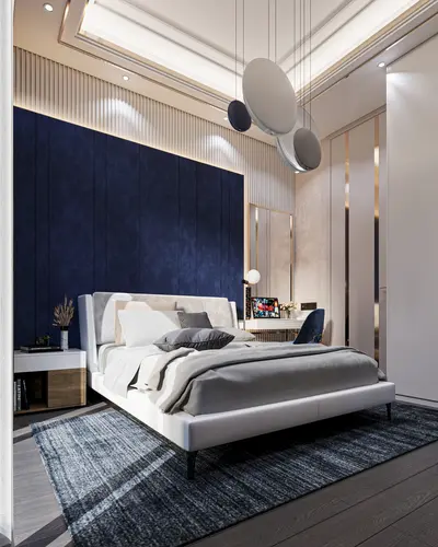 Elegant Modern Bedroom with Stylish Decor and Desk Area. A modern and elegantly designed bedroom featuring a comfortable white bed, dark wooden flooring, a striking blue accent wall, and a stylish desk area with a laptop.