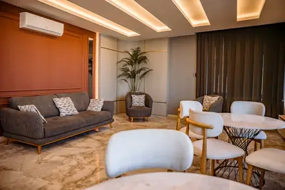 Modern Open-Plan Living and Dining Area. A modern open-plan living and dining area with marble floors, a gray sofa, a round marble table with white chairs, and elegant recessed lighting. Air-conditioned.