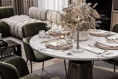 Modern Open-Plan Living and Dining Area with Stylish Decor. Modern open-plan living and dining area. Features a marble dining table with place settings, olive green velvet chairs, and a dried floral centerpiece. A plush sofa in background defines the luxurious style.