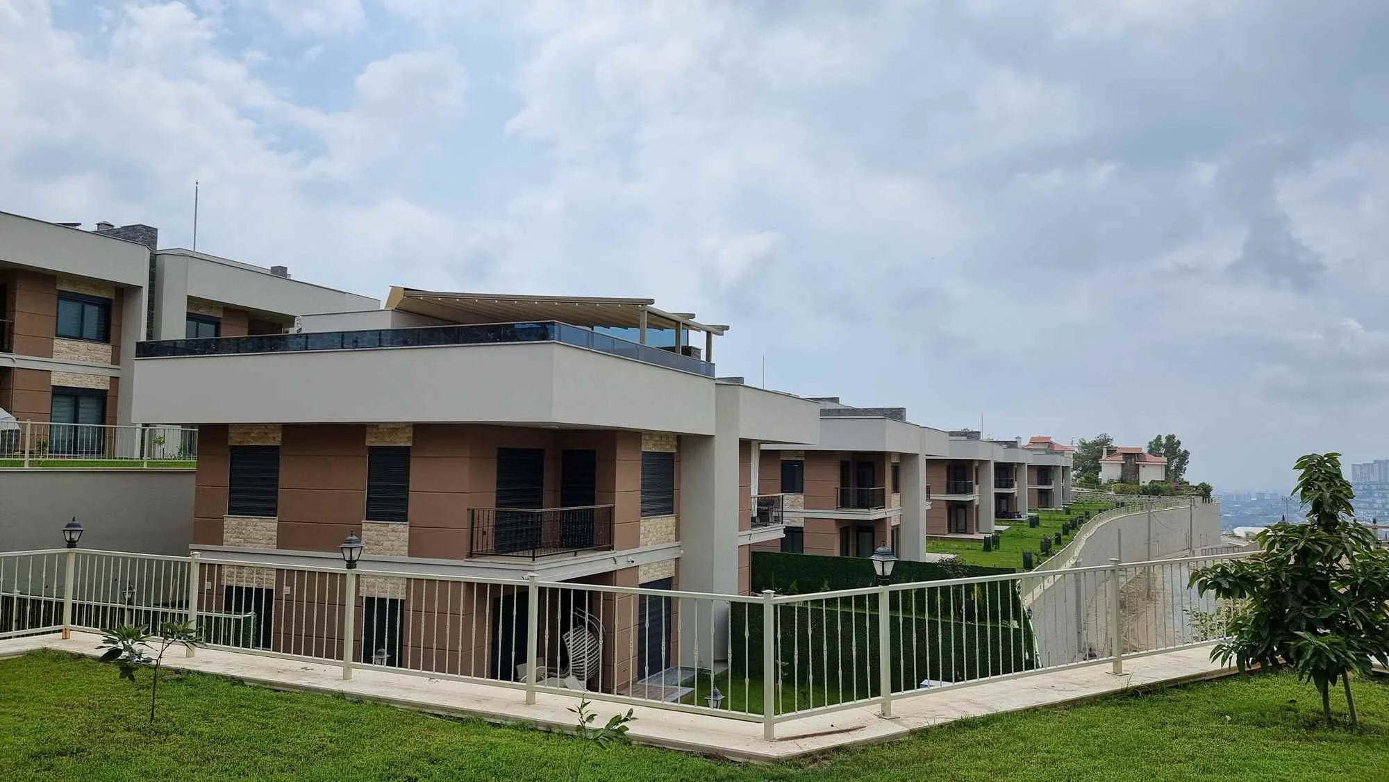 Moderni apartmanski kompleks na brdu s pogledom na grad. Vanjski pogled na moderni stambeni kompleks smješten na zelenom brdu. Sadrži suvremene višespratnice s balkonima i pogledom na udaljeni grad. Dobro održavana arhitektura.