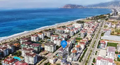 Panoramic Aerial View of Alanya Coastline and Beach. Aerial view of Alanya coastline, Turkey, showcasing modern apartment buildings, a sandy beach, clear blue sea, and distant mountains under a bright sky.