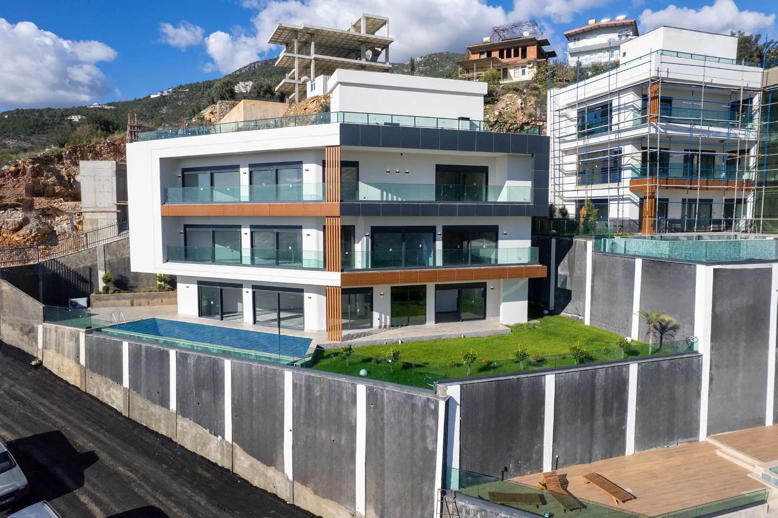 Moderna nekretnina na brdu s privatnim bazenom i balkonima. Vanjski snimak novoizgrađene, moderne višespratne nekretnine na padini brda. Sadrži elegantnu arhitekturu, velike staklene balkone i privatni bazen.