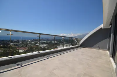 Panoramic Sea, City and Mountain Views from Terrace. A stunning panoramic view overlooking the Mediterranean Sea, a vibrant city, and majestic mountains from a modern outdoor terrace on a bright, sunny day.