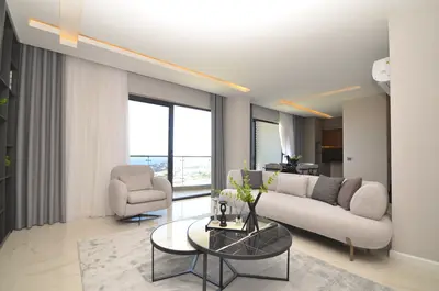 Bright Modern Living Room with Panoramic Sea View. Modern living room featuring sleek tiled flooring, contemporary furniture, and large windows offering a beautiful sea view. Includes direct balcony access and recessed lighting.