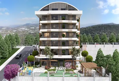 Moderna stambena zgrada s balkonima i uređenim vrtom. Moderna višespratna stambena zgrada izvana s brojnim balkonima, bujnim uređenim vrtom koji uključuje igralište, vanjski šah i prostor za mini golf. Prekrasan planinski pejzaž upotpunjuje pogled.
