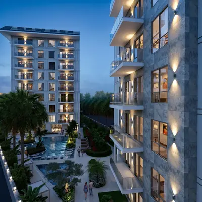 Luxury Apartment Complex with Pool and Landscaped Gardens. An exterior view of a modern residential complex at dusk, showcasing two illuminated buildings, a large swimming pool, and beautifully landscaped gardens. Residents are seen enjoying the outdoor common areas.