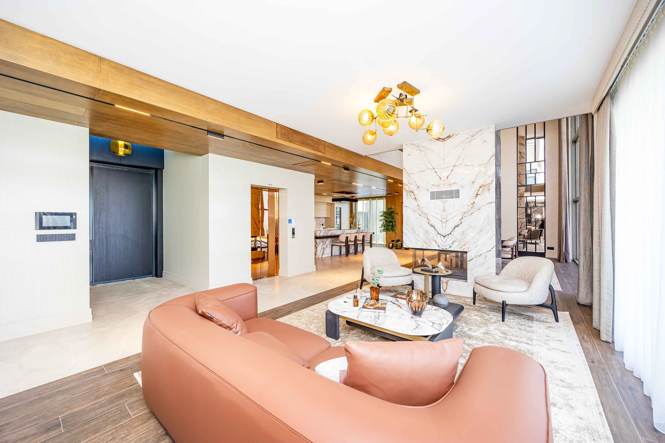 Luxuriöses modernes Wohnzimmer mit Marmorkamin und Aufzug. Geräumiges und luxuriöses modernes Wohnzimmer mit einem beeindruckenden Marmorkamin, einem eleganten Kronleuchter und großen Fenstern. Mit komfortablen modernen Möbeln, Akzenten aus Holz an der Decke und einem privaten goldenen Aufzug.