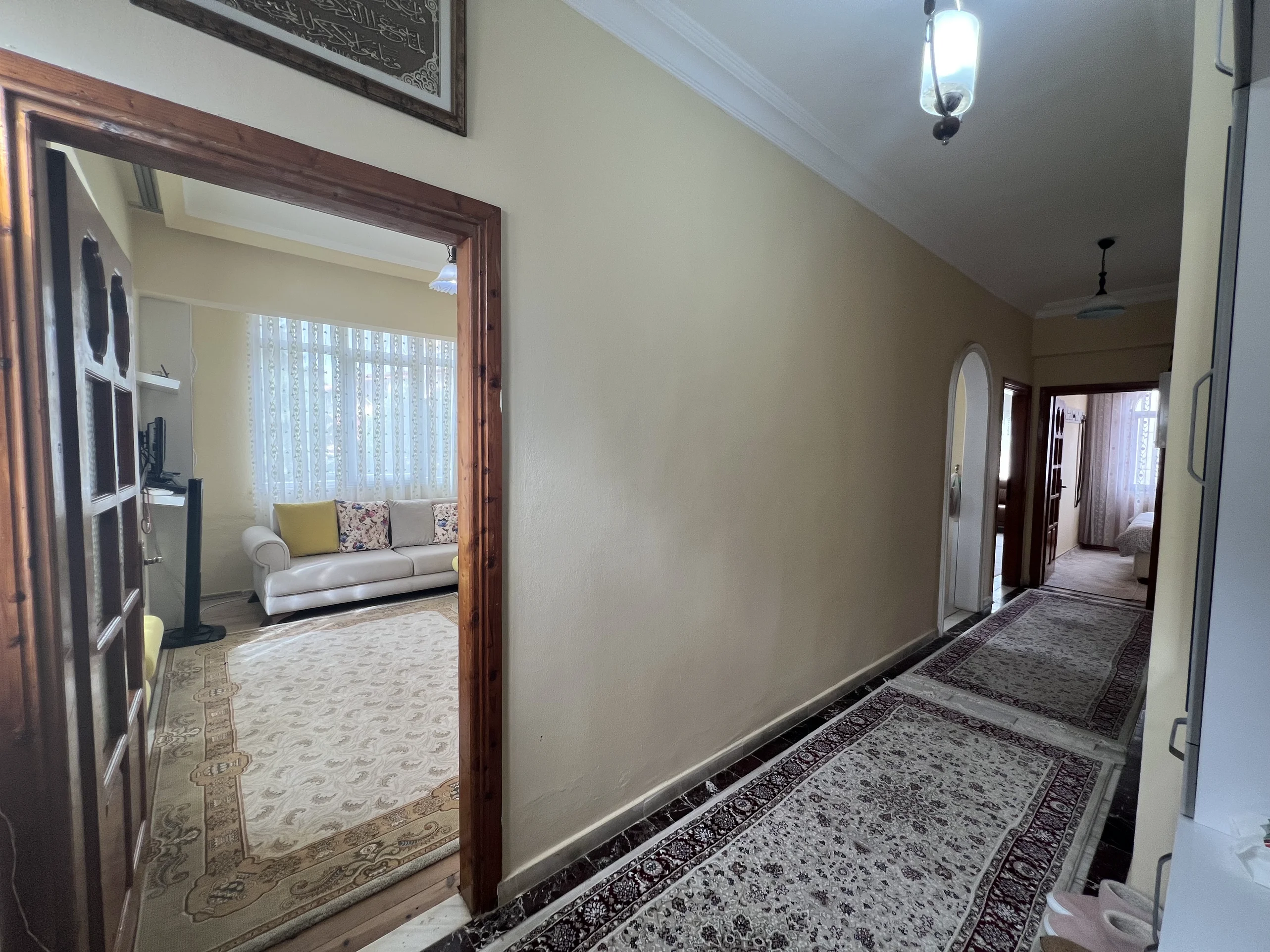 ممر واسع يربط غرفة المعيشة والأجنحة الخاصة. ممر تقليدي بجدران كريمية، وسجاد منقوش فوق أرضية رخامية داكنة، وإطارات أبواب خشبية. يوفر وصولاً إلى غرفة معيشة مشرقة وغرفة نوم مريحة.